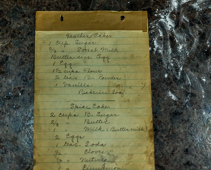 an old, hand-written recipe book on a counter with spilled flour on the right