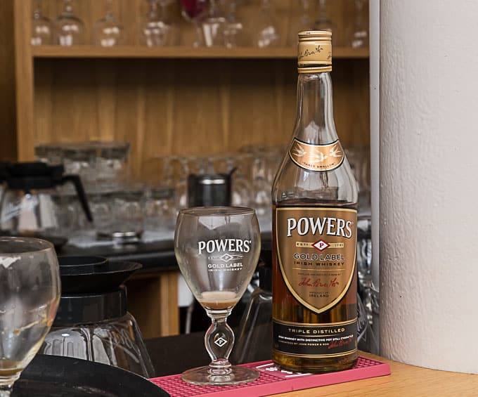 Powers Irish whiskey bottle and a glass on a bar