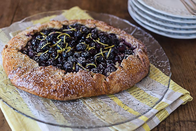 fresh baked blueberry crostata on a glass plate on a striped towel