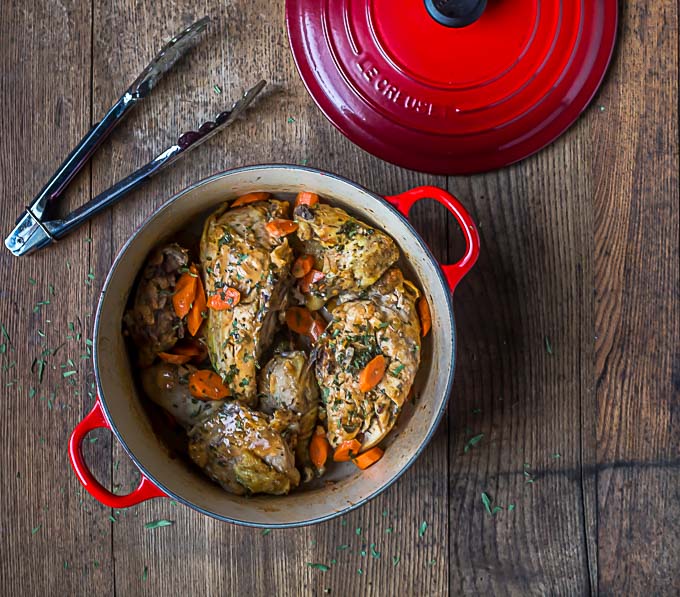 chicken tarragon in a red dutch oven with tongs and the lid above