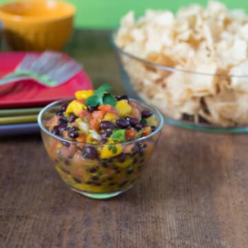 A photo of mango black bean pico de gallo in a clear glass bowl.