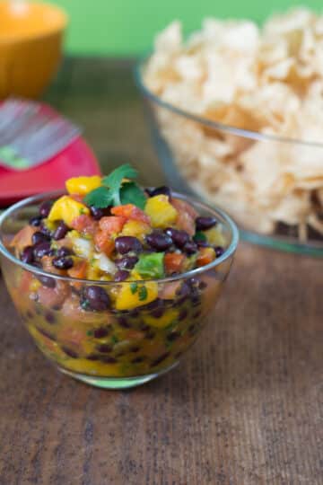 A photo of mango black bean pico de gallo in a clear glass bowl.