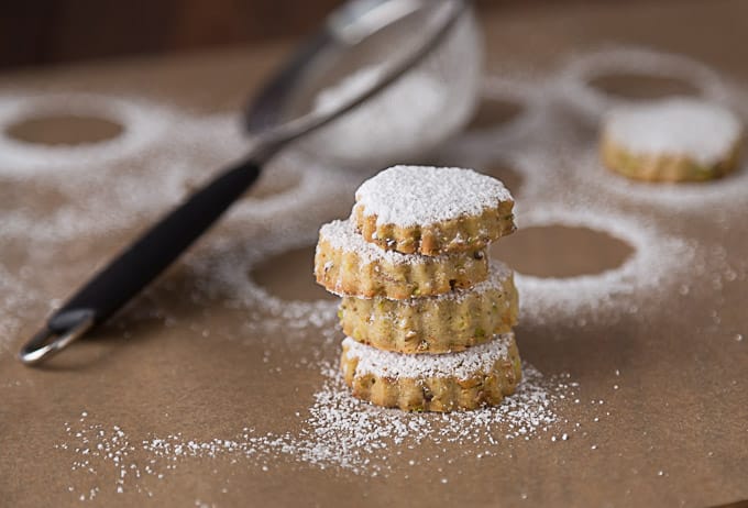 a stack of pistachio rosewater cookies with powdered sugar