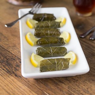 dolmas on a white plate with lemons