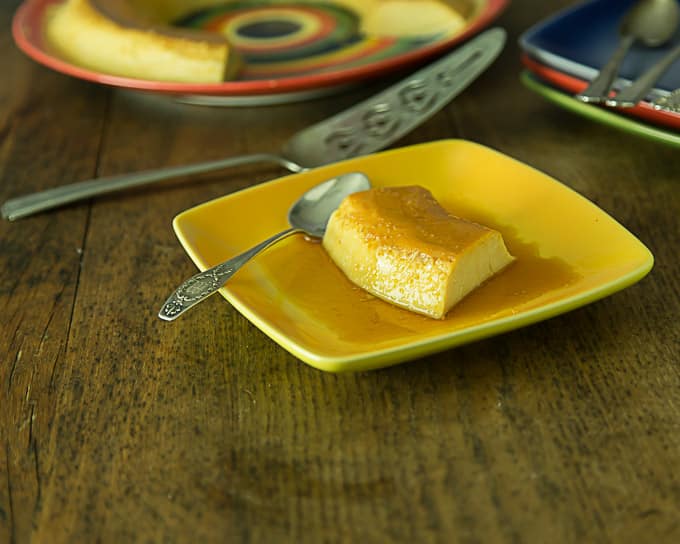 a yellow plate with a slice of no bake flan and a spoon with a cake knife in the back