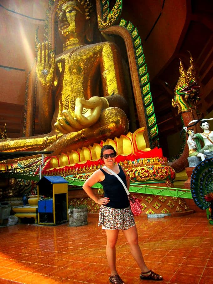 a girl in front of a golden Buddah statue in Thailand 