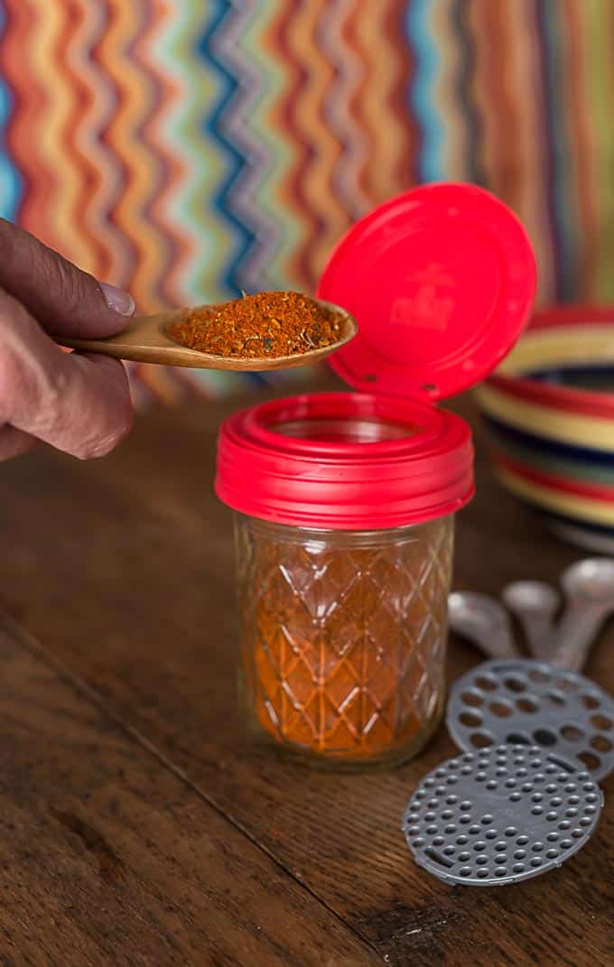 a mason jar filled with red chili powder on a wooden table