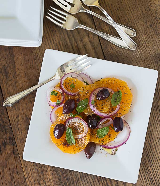 a top dow view of a white plate with turkish orange and onion salad with forks on the top