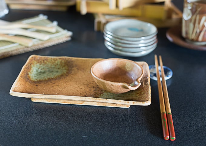 a sushi plate with a soy sauce bowl and chopsticks 