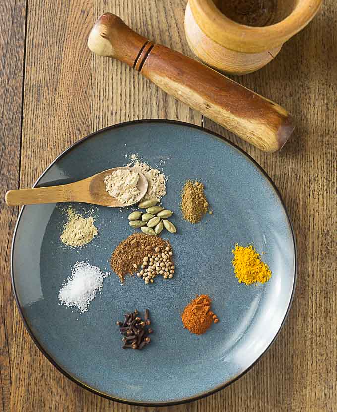 A photo of a blue plate with the spices used to make curry.
