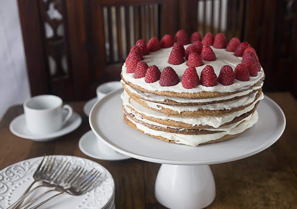 a swedish layeredcake on a cake tray with raspberries and creme 