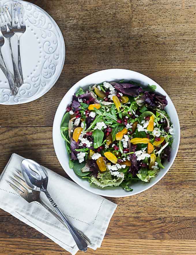 an upward view of a salad bowl with apricots, purple lettuce, and feta cheese