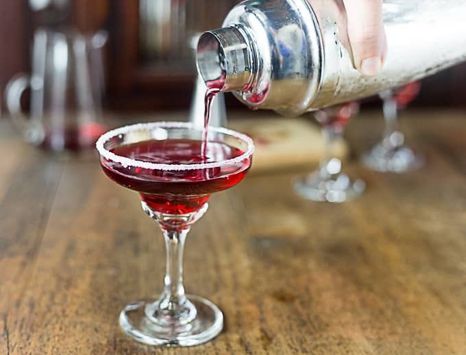 a margarita glass with a shaker pouring pomegranate margarita 