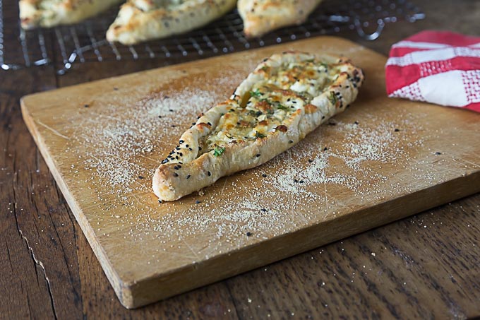 a turkish pastry, pide, on a wooden cutting board with a red napkin