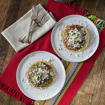 An overhead photo of refried bean tostadas on white plates.