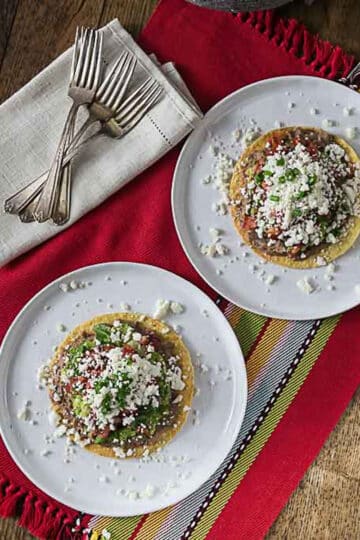 An overhead photo of refried bean tostadas on white plates.