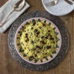 An overhead photo of saffron rice sitting on a ceramic plate with a metal platter.