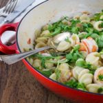 orecchiette with shrimp and arugula in a red serving dish