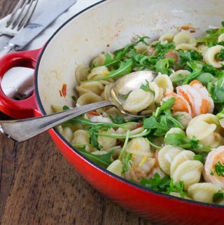 orecchiette with shrimp and arugula in a red serving dish