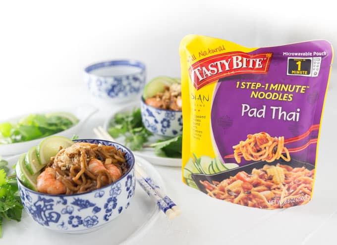 a packet of tasty bite pad thai noodles next to two bowls of prepared shrimp pad thai