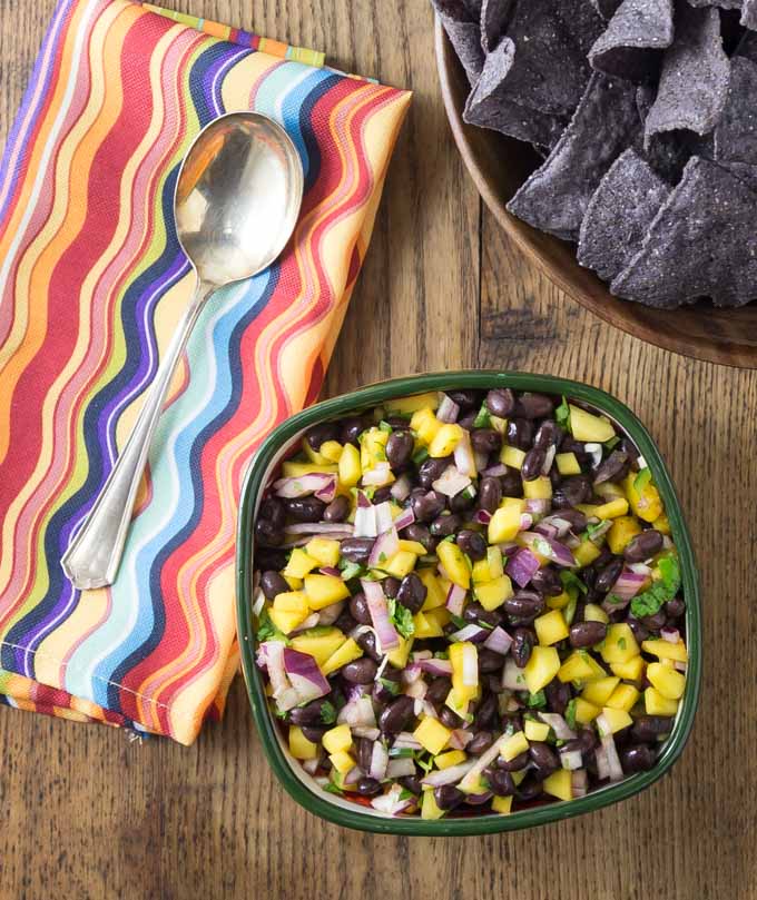 Try this super easy mango black bean salsa! This is my go-to dish to bring to summer picnics. If you can chop and stir this is the salsa for you! I love the sweet, savory and spicy flavors this dish brings. | ethnicspoon.com