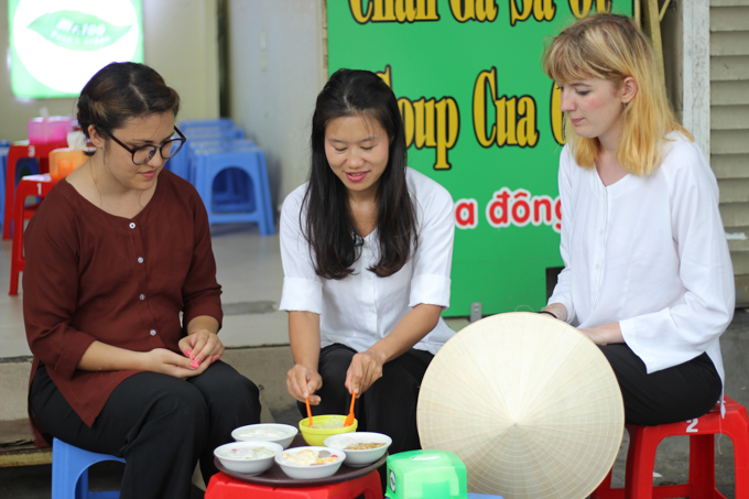 a group of tourists trying Vietnamese dessert with a local