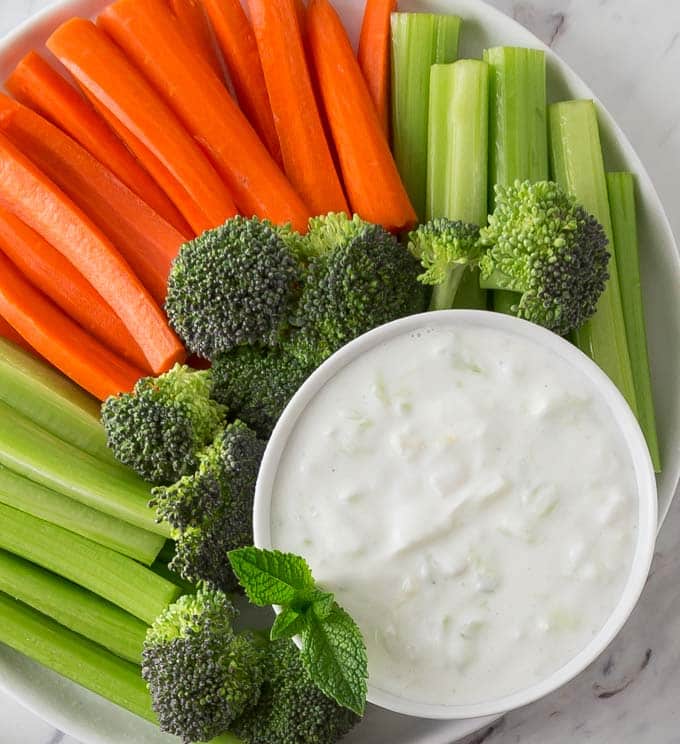 A top down view of a plate of vegetables with a bowl of tzatziki 