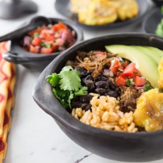 Some of the best Mexican food is so easy to make at home! Slow cooked authentic Mexican pork carnitas burrito bowls is what I am making today. The smell is filling my house and I am getting HUNGRY. Mexican pork carnitas are really the first cousin to pulled pork, a USA favorite. Slow cooker tender and delicious with a nice crispy finish! You will love these authentic Mexican pork carnitas burrito bowls ! Super easy to make in the slow cooker and then crisp up in the oven. Add some pico de gallo, some fried green plantain, avocado and some black beans. | ethnicspoon.com