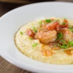When you visit the Southern USA you have a try a bowl of this spicy dish! Some of the best comfort food comes from the American South and shrimp and grits ranks near the top! Shrimp and grits is true Lowcountry cuisine from coastal Carolina and Georgia. Imagine a spicy saucy shrimp with some creamy corn grits with cheese for a nice balance of flavor. This is a must try recipe and feel free to get creative. The grits are a blank canvas to add something spicy to. Like cajun flavors? Add some spicy cajun style shrimp. | ethnicspoon.com