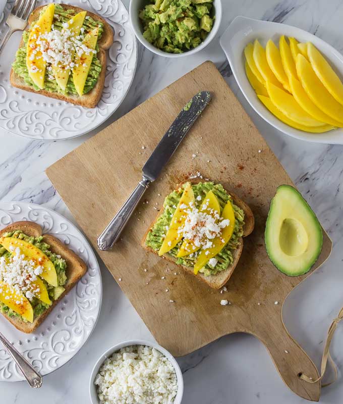 Try a new avocado toast recipe with Latin flair! Creamy avocados with tangy mango, salty queso fresco and a sprinkle of chili powder. The combination of flavors is incredible! | ethnicspoon.com