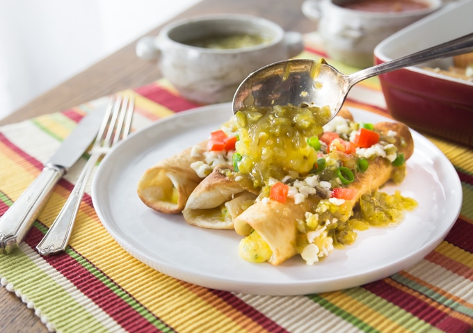 a plate of flautas and a spoon adding more green sauce