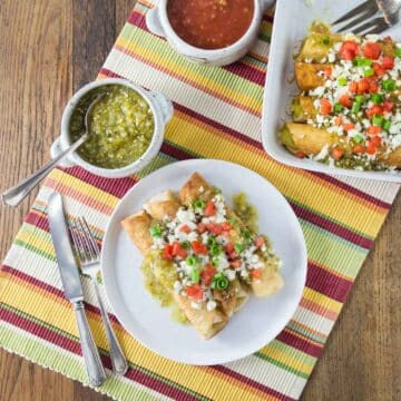 An overhead photo of baked Mexican three cheese flautas with salsa and onions.