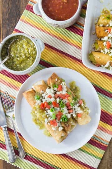 An overhead photo of baked Mexican three cheese flautas with salsa and onions.