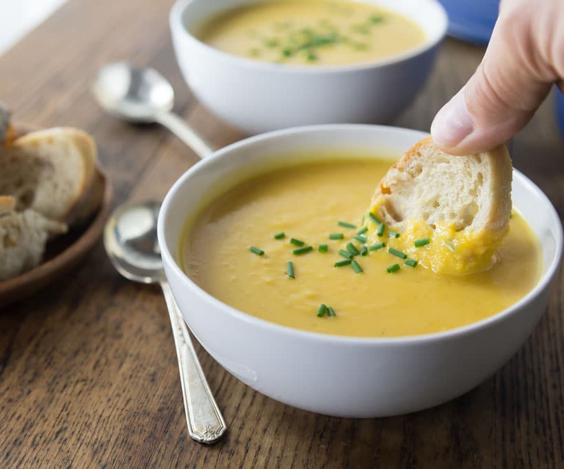 bread dipping into a bowl of squash soup