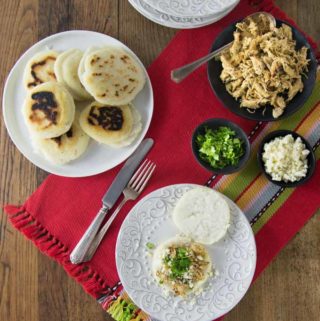 You'll love these nice warm arepas with a crunchy exterior and soft creamy middle. Arepas are a popular dish in Colombia and Venezuela. These are also gluten free made with corn flour or masarepa. I like to fill mine with some spicy shredded chicken and queso fresco. Here is an easy recipe to make arepas at home and the dough comes together quickly and you can brown them on a cast iron skillet or griddle. | ethnicspoon.com