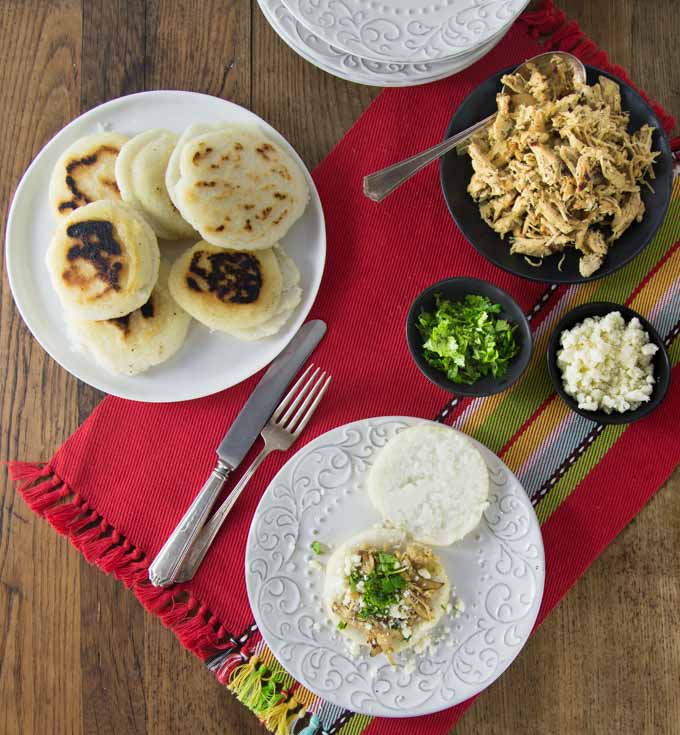 You’ll love these nice warm arepas with a crunchy exterior and soft creamy middle. Arepas are a popular dish in Colombia and Venezuela. These are also gluten free made with corn flour or masarepa. I like to fill mine with some spicy shredded chicken and queso fresco. Here is an easy recipe to make arepas at home and the dough comes together quickly and you can brown them on a cast iron skillet or griddle. | ethnicspoon.com