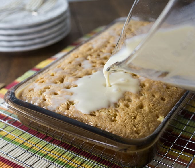 a glass pyrex pouring creme into the poked cake