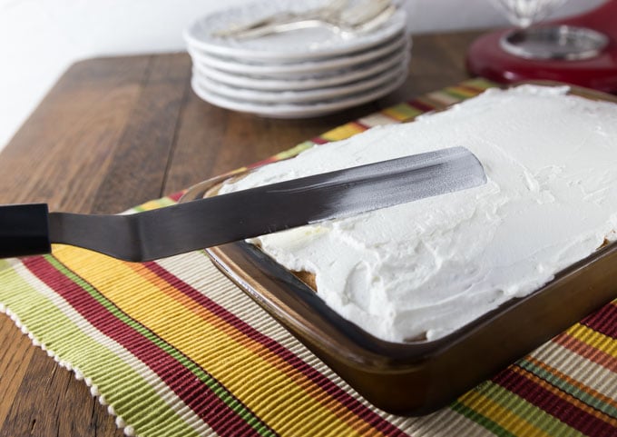 a spatula frosting a cake on a striped placemat
