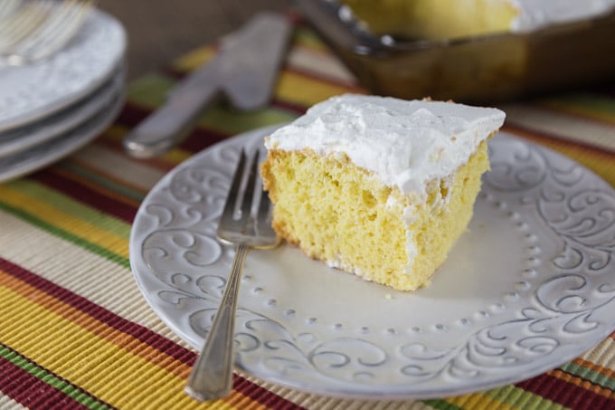 a slice of tres leches cake on a white plate with a fork