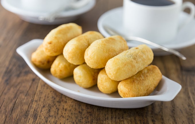 A white plate piled with two rows of carimañolas or yuca fritters.