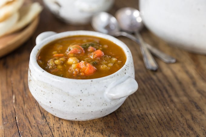 a close up bowl of moroccan lentil soup with two spoons on the right