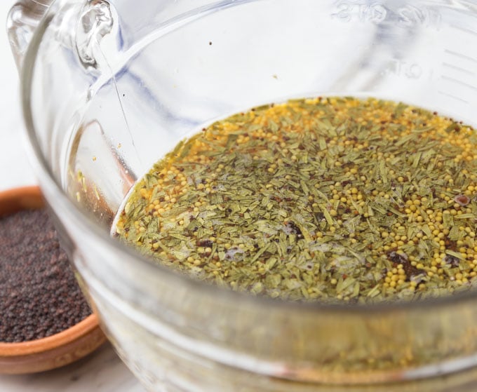 a bowl of mustard spices soaking and a bowl of seeds on the left
