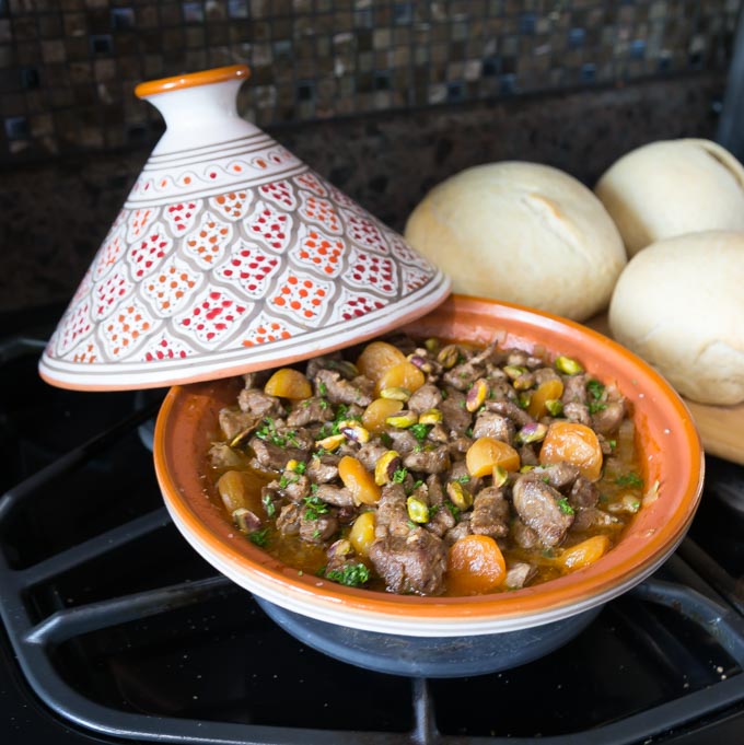 an orange tagine filled with lamb, juice, apricots, and carrots