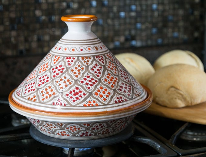an orange tagine on the stove with bread in the back