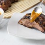 Dry rub the ribs and brush with some BBQ sauce. Refrigerate for 4 hours then bake in the oven for 2 hours. Fire up the grill to finish with a nice crispy brown exterior. You will love this homemade sweet spicy peach bourbon BBQ sauce. | ethnicspoon.com
