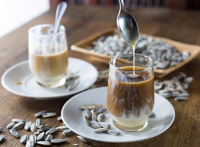 a spoon adding condensed milk to a glass of coffee
