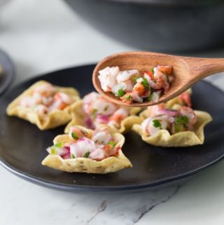 shrimp ceviche on wooden spoon with black plate and chips
