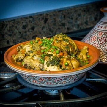 A photo of a Moroccan tagine on a stove with chicken.