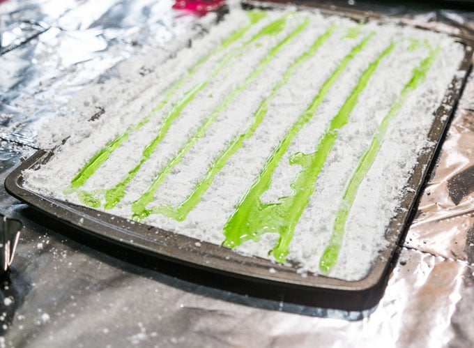 Flavored hard candy poured into powdered sugar troughs on a baking sheet.