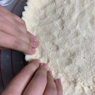 Pressing dough mixture onto removable bottom tart pan.